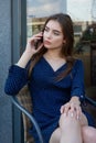 Portrait of a young woman in a cafe on the street sitting at a table and talking on the phone. Lifestyle beauty woman Royalty Free Stock Photo