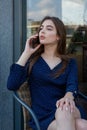 Portrait of a young woman in a cafe on the street sitting at a table and talking on the phone. Lifestyle beauty woman Royalty Free Stock Photo