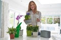 Portrait Of Young Woman Caring For Houseplants Indoors