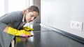 Portrait of young woman cleaning and polishing kitchen surface and countertop while doing house work Royalty Free Stock Photo