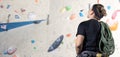 Portrait of young woman climber with a rope tracking the indoor climbing wall, sport activity concept