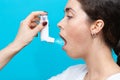 Portrait of a young woman in close-up, who is being inhaled medication. Side view. Blue background Royalty Free Stock Photo