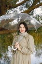 Portrait of a young woman in a coat under a transparent umbrella Royalty Free Stock Photo