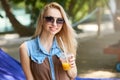 Portrait of young woman with cocktail glass chilling in the tropical sun near swimming pool on a deck chair with palm Royalty Free Stock Photo