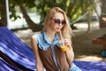 Portrait of young woman with cocktail glass chilling in the tropical sun near swimming pool on a deck chair with palm Royalty Free Stock Photo