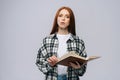 Portrait of young woman college student holding opened books and looking at camera on gray background. Royalty Free Stock Photo