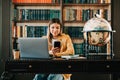 Portrait of young woman college student using mobile phone, preparing for test exam, writing essay doing homework in the library Royalty Free Stock Photo