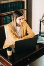 Portrait of young woman college student using mobile phone, preparing for test exam, writing essay doing homework in the library Royalty Free Stock Photo