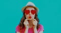 Portrait young woman covering her eyes with red heart shaped lollipops on a blue background Royalty Free Stock Photo