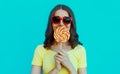 Portrait young woman covering her lips with lollipop on a blue background Royalty Free Stock Photo