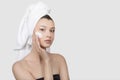 Portrait of a young woman with cream on her face. hand touch to the cheek. A towel on her head Royalty Free Stock Photo