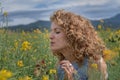 Portrait of young woman with curly hair enjoying scent of blooming tree flowers in garden on sunny summer day. Royalty Free Stock Photo