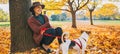 Young woman with cute dog sitting under tree in autumn park Royalty Free Stock Photo