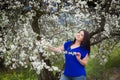 Portrait of a young woman holding a brunch of blossoming plum tree in garden, happily smiling, looking at the sky Royalty Free Stock Photo