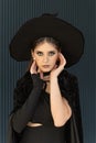 Portrait of a young woman with dark makeup wearing a black hat. Beautiful woman dressed in black. Halloween party Royalty Free Stock Photo