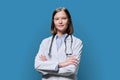 Portrait of young woman doctor student intern in white coat on blue background Royalty Free Stock Photo