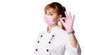 Portrait of young woman doctor or nurse in white medical uniform, gloves and protective mask gesturing OK sign