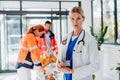 Portrait of young woman doctor with rescuers in background.