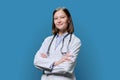 Portrait of young woman doctor student intern in white coat on blue background Royalty Free Stock Photo