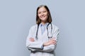 Portrait of young woman doctor student intern in white coat on grey background Royalty Free Stock Photo