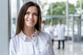 Portrait of young woman doctor with white coat standing in hospital. Royalty Free Stock Photo