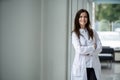 Portrait of young woman doctor with white coat standing in hospital. Royalty Free Stock Photo