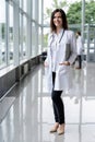 Portrait of young woman doctor with white coat standing in hospital. Royalty Free Stock Photo