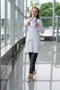 Portrait of young woman doctor with white coat standing in hospital. Royalty Free Stock Photo