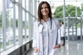 Portrait of young woman doctor with white coat standing in hospital. Royalty Free Stock Photo