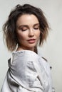 Portrait of young woman with downcast eyes. Female posing in milky white corduroy shirt