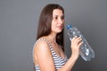 Happy woman holds a bottle of water. Portrait of a young woman drinks water from a bottle