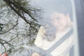 Portrait of a young woman driver behind the wheel of a car. View from behind the glass. A woman smiles