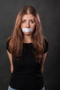 Portrait of a young woman with duct tape sealed in her mouth, restriction of freedom of speech and censored Royalty Free Stock Photo