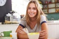 Portrait Of Young Woman Eating Breakfast In Kitchen