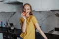 Portrait of young woman eating apple in kitchen Royalty Free Stock Photo