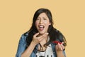 Portrait of a young woman eating red hot chili pepper over colored background Royalty Free Stock Photo