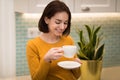 Portrait of young woman enjoying aromatic morning coffee in kitchen