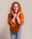 Portrait of young woman in eyeglasses and knit hat smiling and gesturing against white background Royalty Free Stock Photo