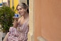 Portrait of young woman with fair hair wearing summer pink striped dress, holding blue cup, enjoying smell of coffee. Royalty Free Stock Photo