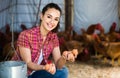 Portrait of young woman farmer holding fresh eggs in hands in henhouse