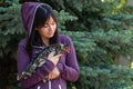 Portrait of a young woman with a feathered friend speckled chicken against a blue spruce