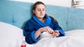 Portrait of young woman feeling unwell lying in bed and taking pills from bottle Royalty Free Stock Photo