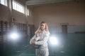 A portrait of a young woman fencer holding her helmet at the school gym