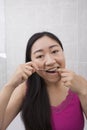 Portrait of young woman flossing her teeth in bathroom Royalty Free Stock Photo