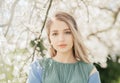 Portrait of young woman in the flowered garden in the spring time. Girl dressed in green dress Royalty Free Stock Photo