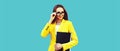 Portrait of young woman with folder wearing eyeglasses, yellow business suit on blue background Royalty Free Stock Photo