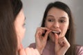 Portrait of young woman is cleaning teeth with dental floss smiling in bathroom. Royalty Free Stock Photo