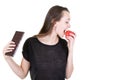 Portrait of young woman with fruit apple red and chocolate being tempted but trying to be healthy