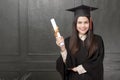 Portrait of young woman in graduation gown smiling and cheering on black background