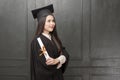 Portrait of young woman in graduation gown smiling and cheering on black background